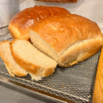 sliced soft sandwich bread on wire cooling rack with bread knife